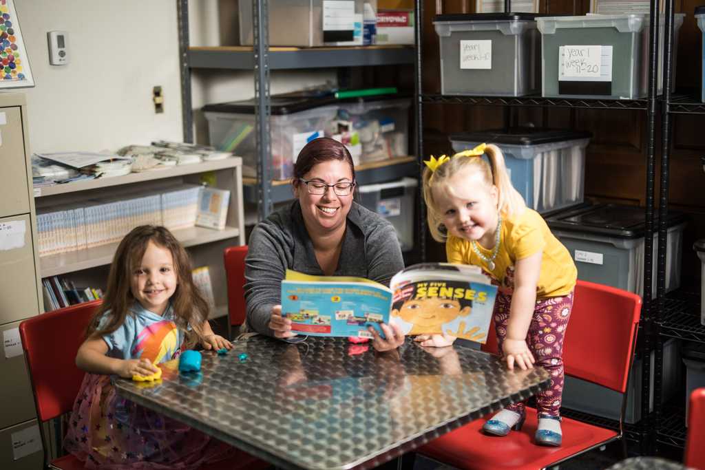 Woman reading a book to two little girls